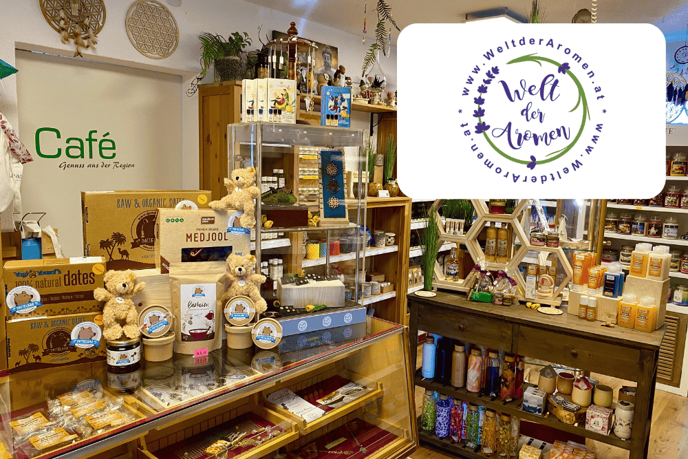 Im Inneren des gemütlichen Ladens sind Regale mit Naturprodukten, Honig, Marmeladen, Plüschbären und Geschenkartikeln zu sehen. Ein Café-Schild und das Logo der Website Welt der Aromen sind ebenfalls in der Szene zu sehen.